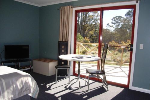 a room with a bed, chair, table and a window at Highland Cabins and Cottages at Bronte Park in Bronte