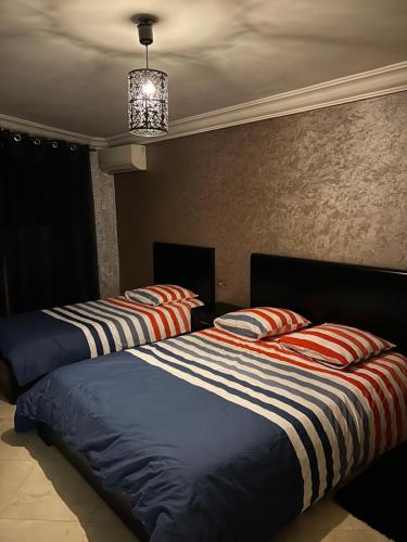 two beds with striped pillows in a bedroom at Duplex haut standing à 5min de la plage2 in Agadir