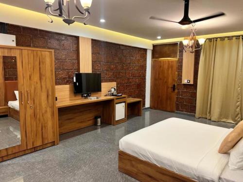 a bedroom with a bed and a desk with a tv at Udaya Resort in Palakkad