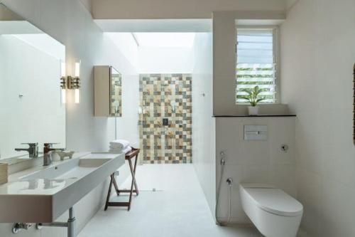 une salle de bain blanche avec toilettes et lavabo dans l'établissement amã Stays & Trails Forest Home, Hosur, à Hosur