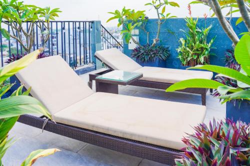 a patio with two white couches and plants at Bonny Boutique Hotel Da Nang in Da Nang