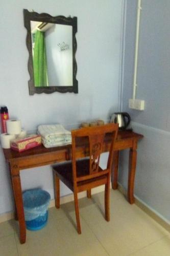 a wooden table with a chair and a mirror at Cheers Garden Chalet in Kampung Tekek