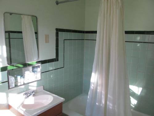 ein Bad mit einem Waschbecken und einer Dusche mit einem Spiegel in der Unterkunft Hancock Motel in Hancock