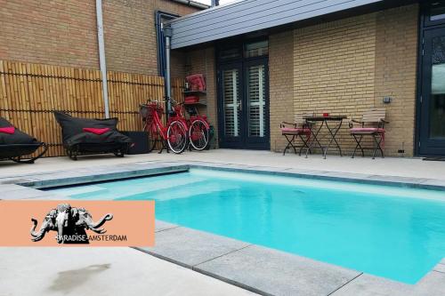 a swimming pool in front of a house with bikes at Paradise Amsterdam bungalow of 80 m2 with private pool - inclusive, breakfast, parking, use of bikes, tourist tax and much more in Zandvoort