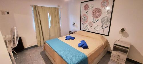 a bedroom with a bed with blue slippers on it at Lajas Negras Aparts - Departamento céntrico in Catriel