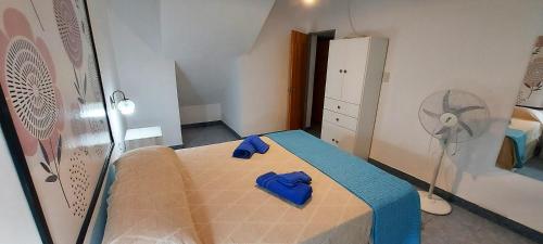 a bedroom with a bed with blue sheets and a fan at Lajas Negras Aparts - Departamento céntrico in Catriel
