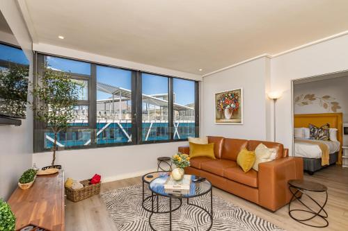 sala de estar con sofá, cama y ventanas en Beautiful Family Apartment with amazing views @ 16 on Bree en Ciudad del Cabo
