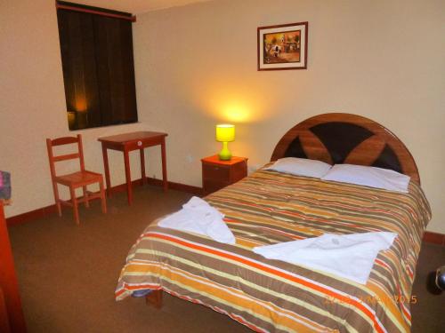 1 dormitorio con 1 cama, 1 mesa y 1 silla en PosadaInka, en Cusco
