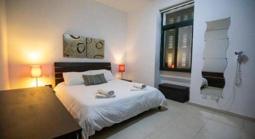 a bedroom with a bed and a table and a window at VBH Apartament SLIEMA in Sliema