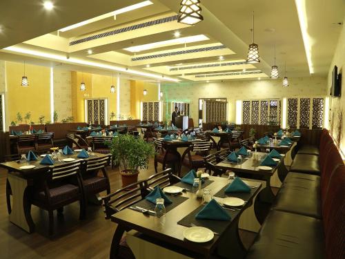 a dining room with tables and chairs with blue napkins at Renest Tirupati in Tirupati