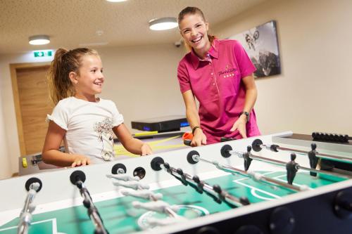 two women standing next to a ping pong table at Der Postwirt in Söll