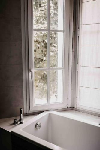 une baignoire blanche devant une fenêtre dans l'établissement Belle maison dans un village de charme, à Moisson