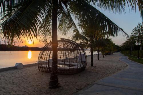 a hammock on a beach with a palm tree at Castle Bayview Resort & Spa in Kampot