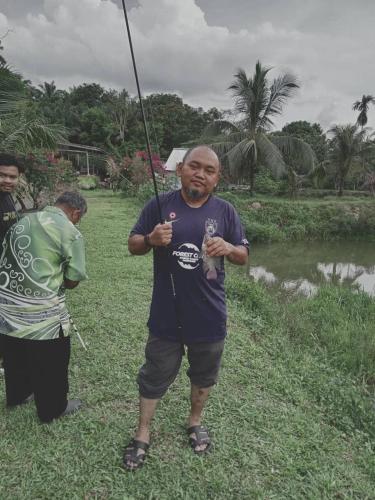 a man holding an umbrella in the grass at Tmn Rekreasi Cikgu Haron in Labis
