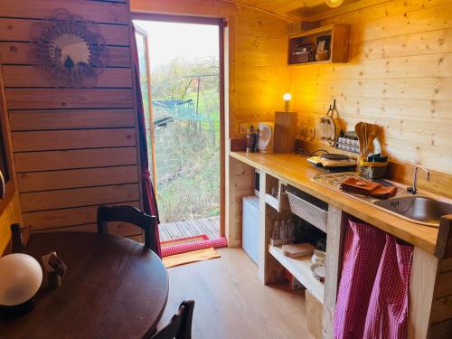 uma cozinha com uma mesa, um lavatório e uma janela em La Rouloulotte em Durbuy