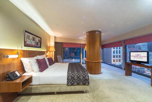 イスタンブールにあるクラウンプラザ イスタンブール ハルビエのベッドとテレビが備わる広いホテルルームです。