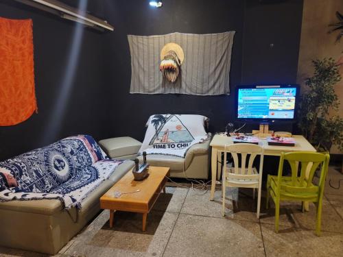 a living room with a couch and a table with a monitor at Doobaki Hostel in Gyeongju