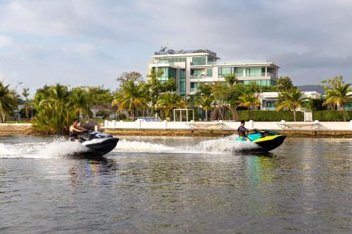 two people are riding on boats in the water at Castle Bayview Resort & Spa in Kampot