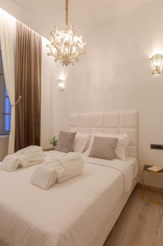 two beds in a white bedroom with a chandelier at Residenza di Fedralia in Nafplio