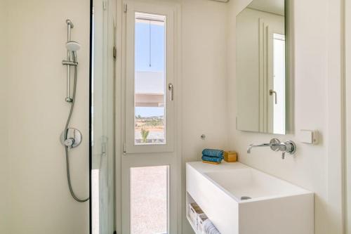 une salle de bain blanche avec un lavabo et un miroir dans l'établissement Villa Lámpsi - Spacious & modern, à Isterni
