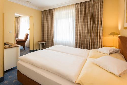 a hotel room with a large white bed and a desk at Seehotel Frankenhorst - BW Signature Collection in Schwerin