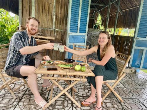 un hombre y una mujer sentados en una mesa con bebidas en VulunVili Homestay, en Tây Ninh