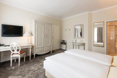a hotel room with a bed and a desk and a tv at Seehotel Frankenhorst - BW Signature Collection in Schwerin