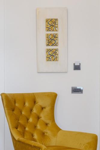 a yellow chair in a room with a picture on the wall at Residenza di Fedralia in Nafplio