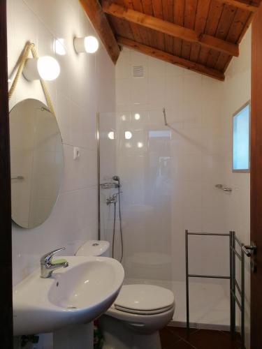 a bathroom with a sink and a toilet and a mirror at Casa Pedra & Cal in Paredes de Coura