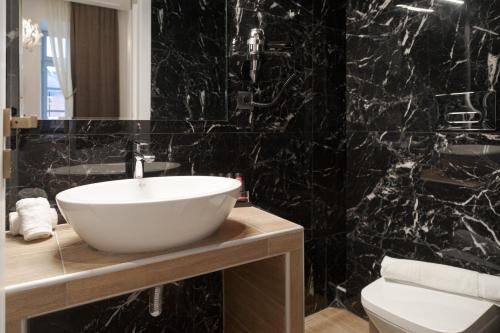 a bathroom with a white sink and a black wall at Residenza di Fedralia in Nafplio