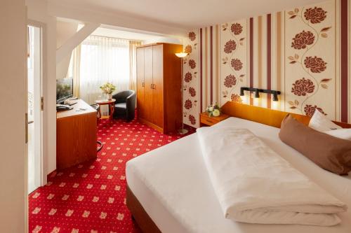 a hotel room with a white bed and a desk at Hotel Berlin in Leipzig