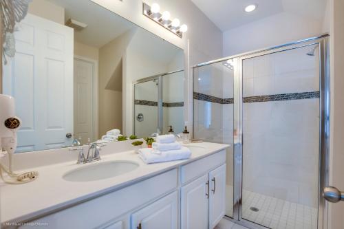 ein weißes Bad mit einem Waschbecken und einer Dusche in der Unterkunft Solara Resort - 5 Bed 4,5 Baths TOWNHOME in Orlando