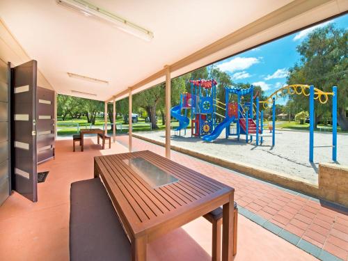 a living room with a table and a playground at Acclaim Rose Gardens Beachside Holiday Park in Albany
