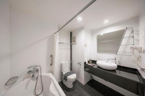 a bathroom with a tub and a sink and a toilet at At 115 Hotel By Rompo in Bangkok