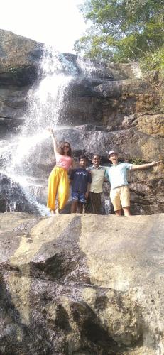 a group of people standing in front of a waterfall at WinterHome homestay in Munnar