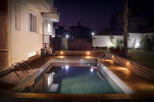 een verlicht zwembad in een achtertuin 's nachts bij Nirvana Home in Kathmandu