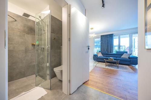a bathroom with a shower and a blue couch at Glow Apartments, Letnica - Apartamenty Przystań Siódme Niebo in Gdańsk