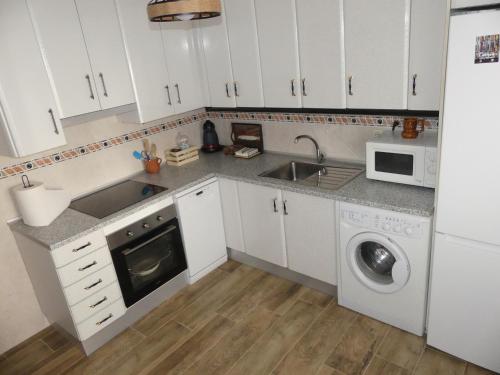 a kitchen with white cabinets and a sink and a dishwasher at Casa Carrasquillas in Cañada del Hoyo