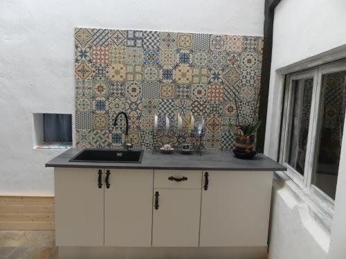 a kitchen with a sink and a tile wall at Casa Carrasquillas in Cañada del Hoyo