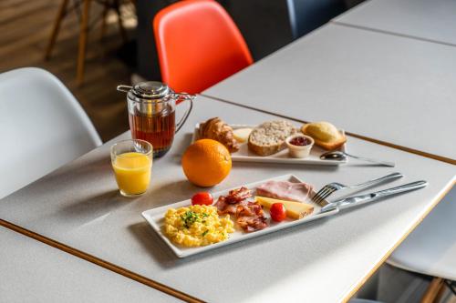 奧爾良的住宿－ibis Orléans Centre Foch，一张桌子,上面放着一盘早餐食品和橙汁
