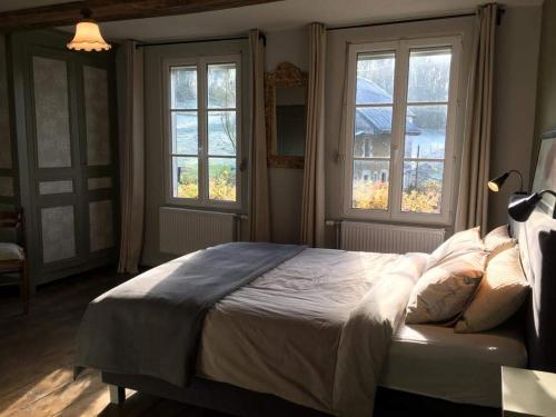 a bedroom with a bed and two windows at BenB La Fosse Bleue in Signy-lʼAbbaye