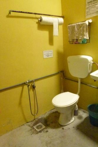 a bathroom with a toilet and a yellow wall at Cheers Garden Chalet in Kampung Tekek