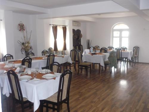 a dining room with tables and chairs with white tablecloths at Pensiunea Cristiana - Murighiol in Murighiol