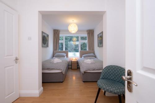een kamer met 2 bedden, een stoel en een raam bij Modern apt near gardens with large decking area - Vivre Retreats in Bournemouth