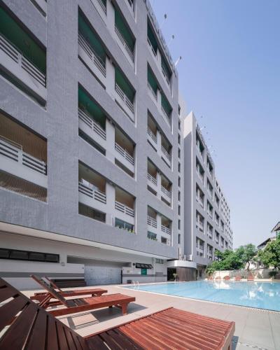 an apartment building with a swimming pool in front of it at At 115 Hotel By Rompo in Bangkok