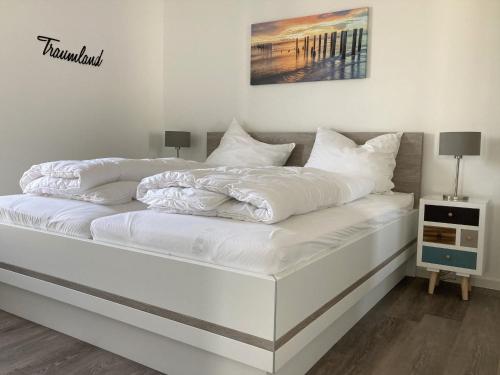 Una cama blanca con sábanas blancas y almohadas. en 49 1 N Nordkoje, en Wangerland