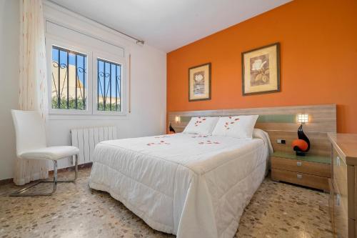a bedroom with a white bed and an orange wall at Llastres in Miami Platja