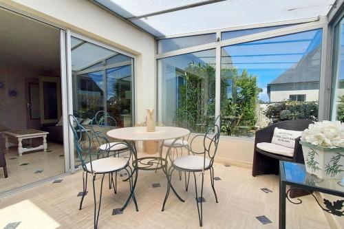 einen Wintergarten mit einem Tisch und Stühlen in einem Zimmer in der Unterkunft Maison côte sauvage classement 3 in Quiberon
