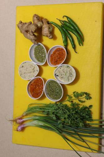 a yellow cutting board with different dips and vegetables at Hotel Woodside Prestige in Tirupati