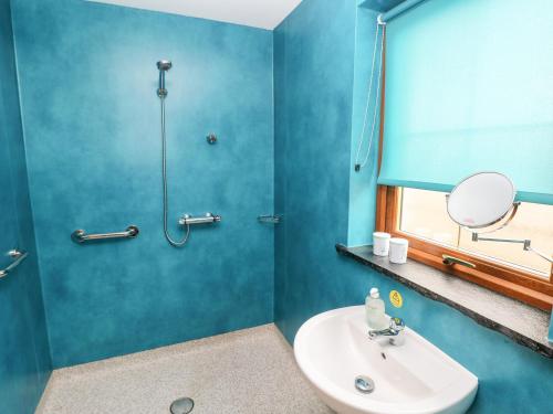 a blue bathroom with a sink and a shower at Cranny in Narberth